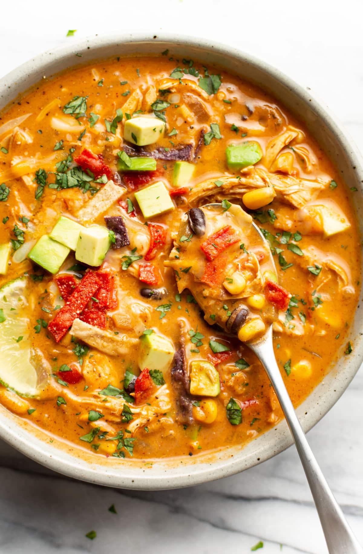 Eine Schüssel Hähnchen-Enchilada-Suppe mit einem Löffel