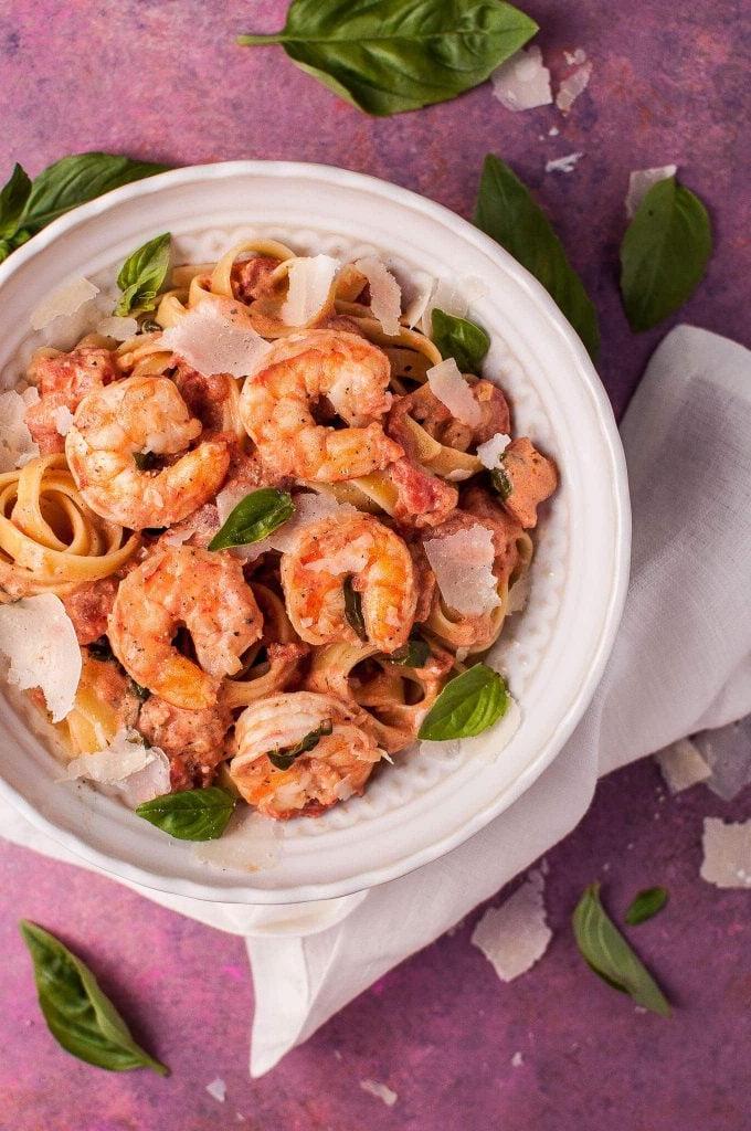 Eine weiße Schale mit Garnelen-Pasta in Rosé-Soße und geriebenem Parmesan