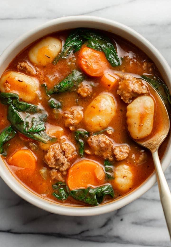 Ein Teller Wurst-Gnocchi-Suppe mit einem Löffel