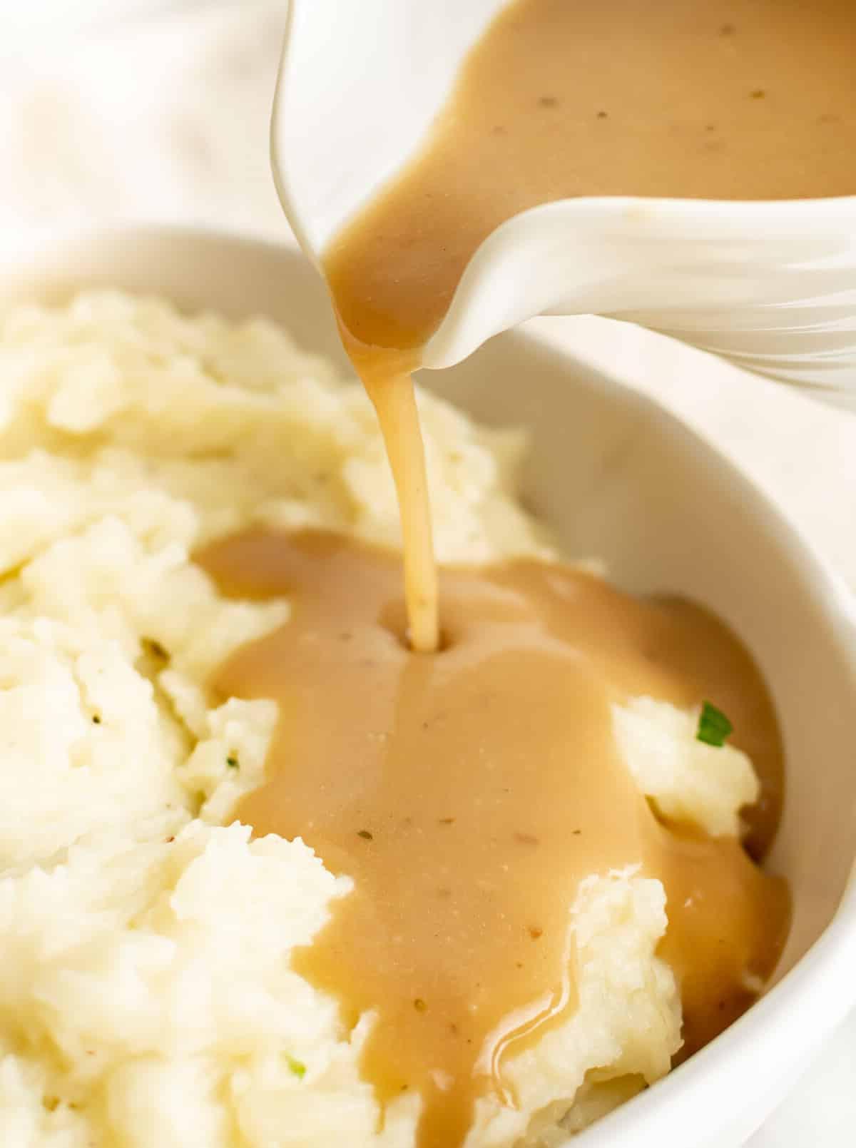 pouring brown gravy onto mashed potatoes