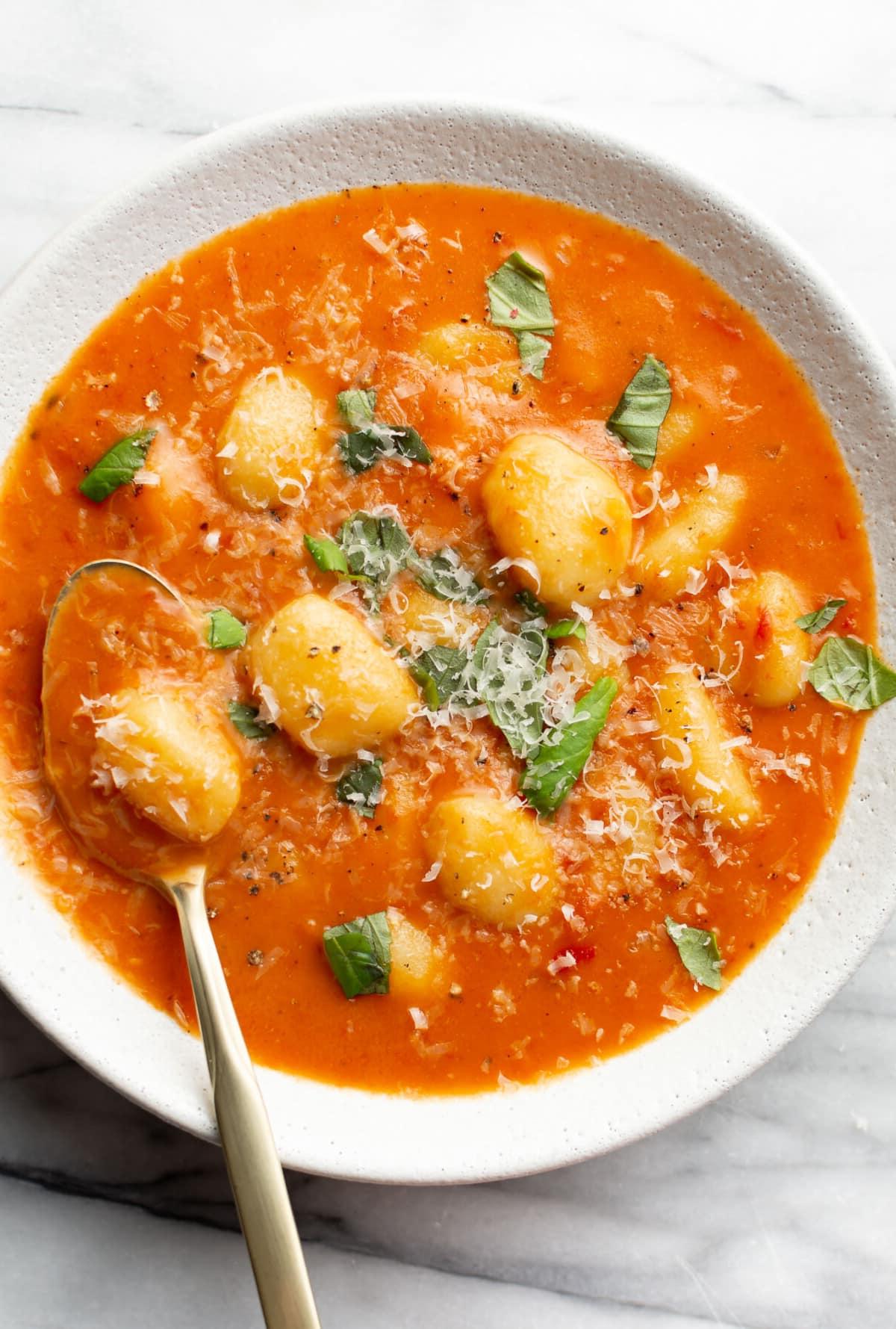 Cremige Tomaten-Gnocchi-Suppe 2 Eine Schüssel cremige Tomaten-Gnocchi-Suppe mit einem Löffel