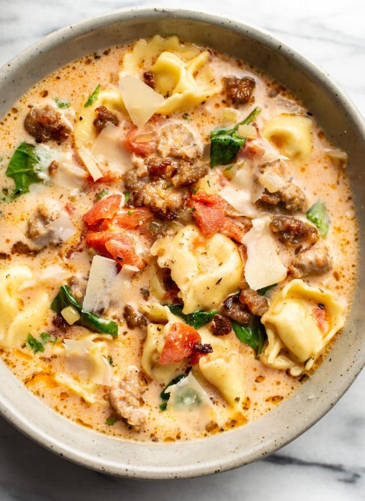 Italienische Salsiccia-Tortellini-Suppe 2 Eine Nahaufnahme einer Schale italienischer Wurst-Tortellini-Suppe, garniert mit gehobeltem Parmesan