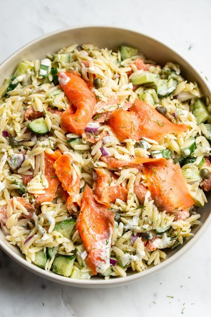 Orzo-Salat mit geräuchertem Lachs in einer beigen Servierschüssel