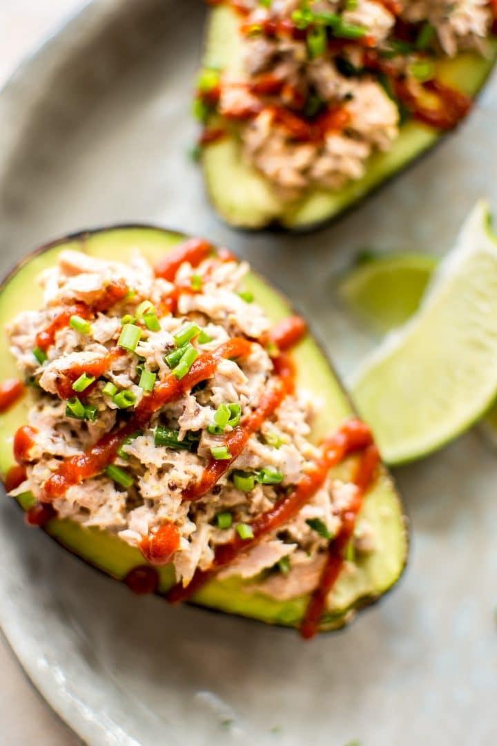 Pikante Thunfisch-Avocado-Hälfte neben Limettenspalten auf einem Teller angerichtet
