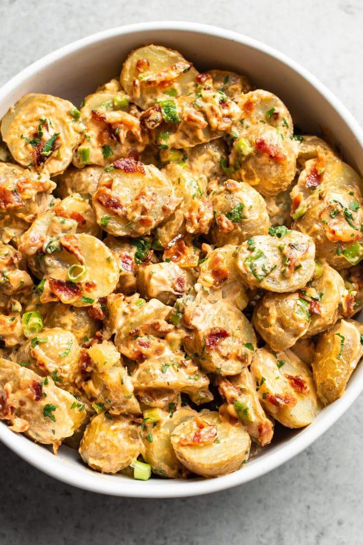 Speck-Kartoffelsalat in einer weißen Servierschüssel