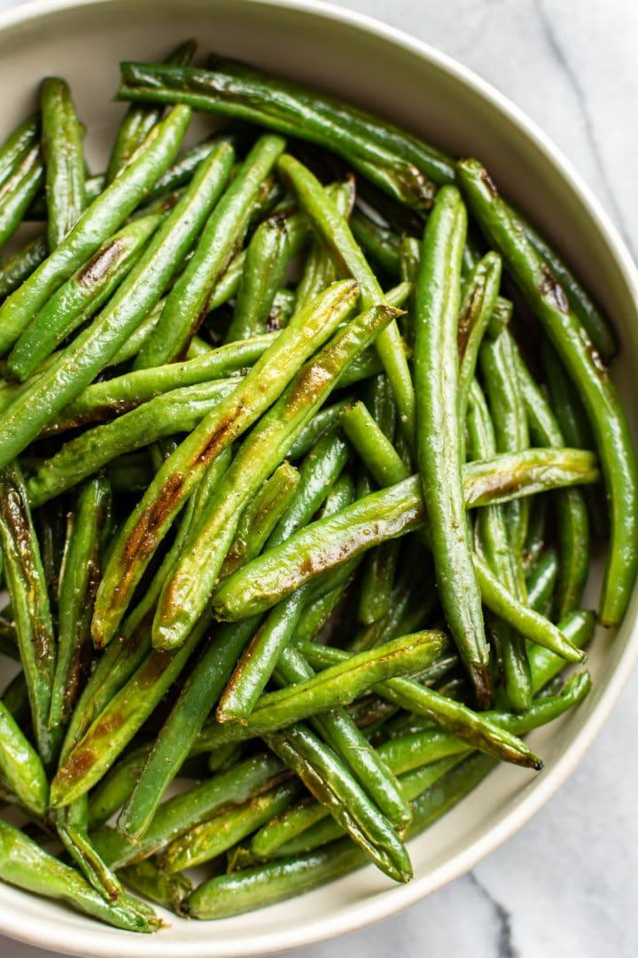 Nahaufnahme von knusprig gerösteten grünen Bohnen mit Knoblauch