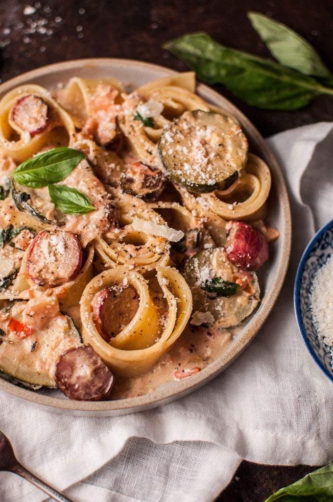 Teller mit cremiger Sommergemüse Pasta und gebratenen Radieschen