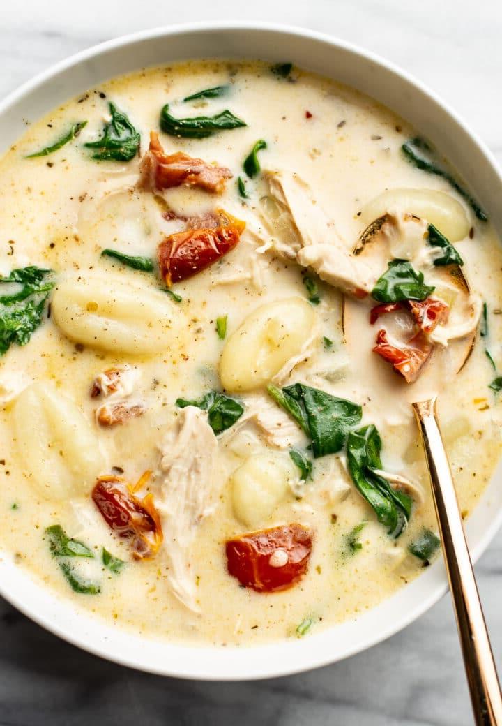 Ein Teller mit cremiger Toskanischer Hähnchen-Gnocchi-Suppe und einem Löffel