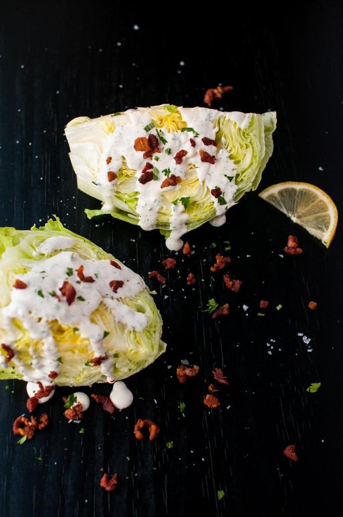 Zwei Eisbergsalat-Keile mit Ranch-Dressing, Speck und einer Zitronenscheibe