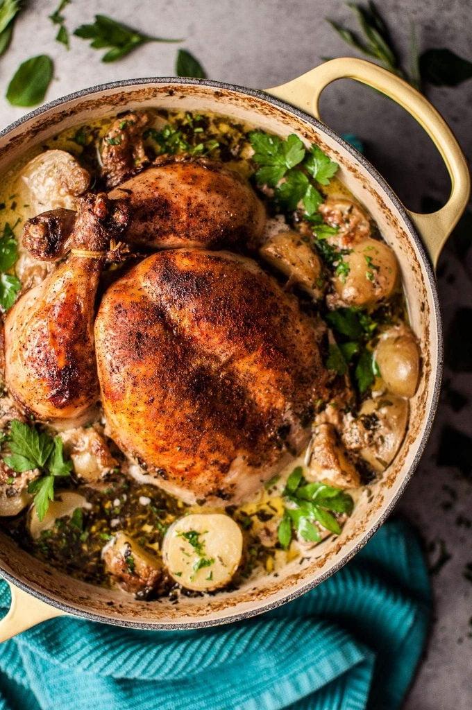 creamy lemon and herb roasted whole chicken in a pot with little potatoes