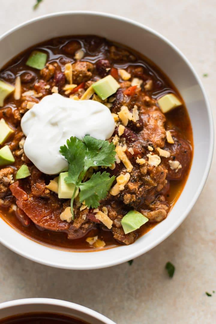 Nahaufnahme einer weißen Schale mit Instant Pot Puten-Chili, garniert mit Sauerrahm