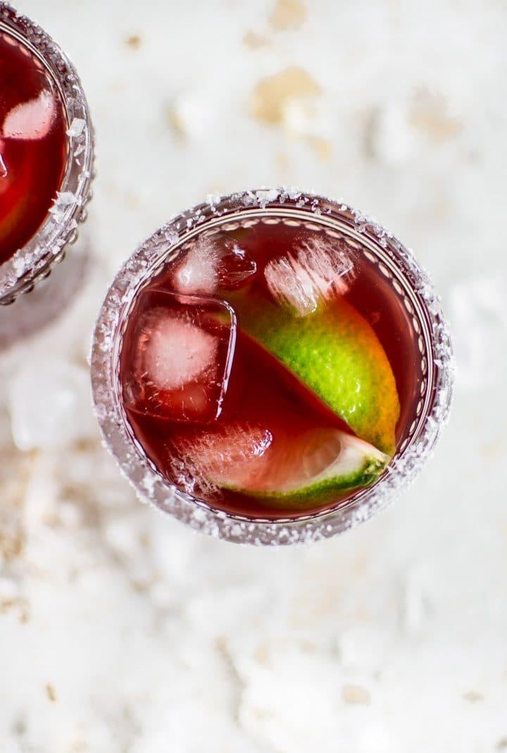 Nahaufnahme eines Granatapfel Margaritas auf Eis mit Limettenspalten