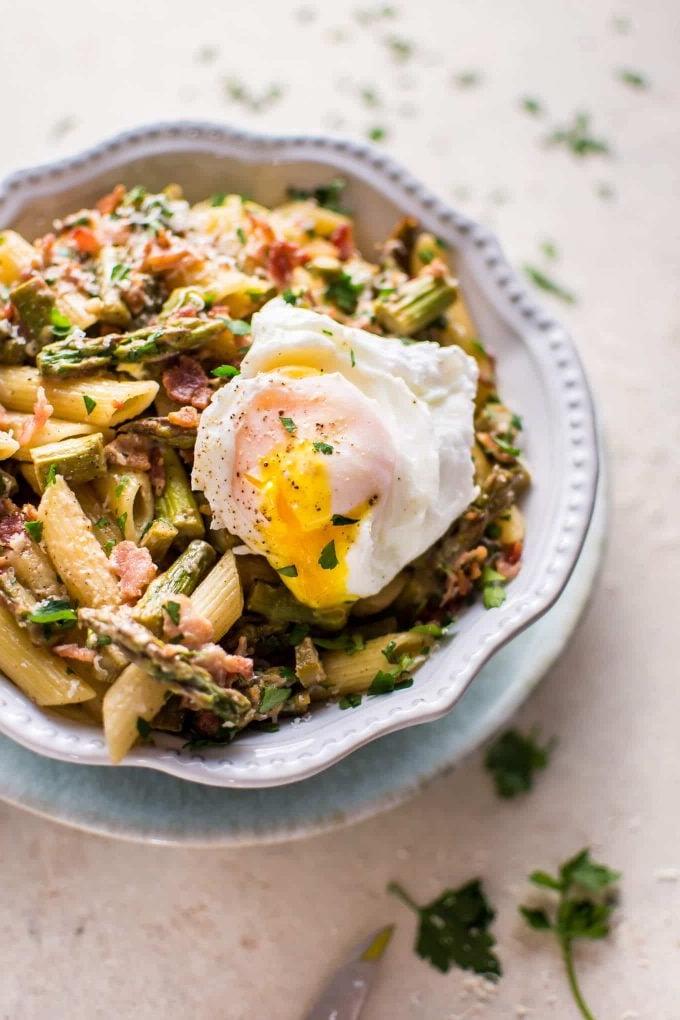 Schüssel mit Spargel-Speck-Pasta, gekrönt mit einem pochierten Ei