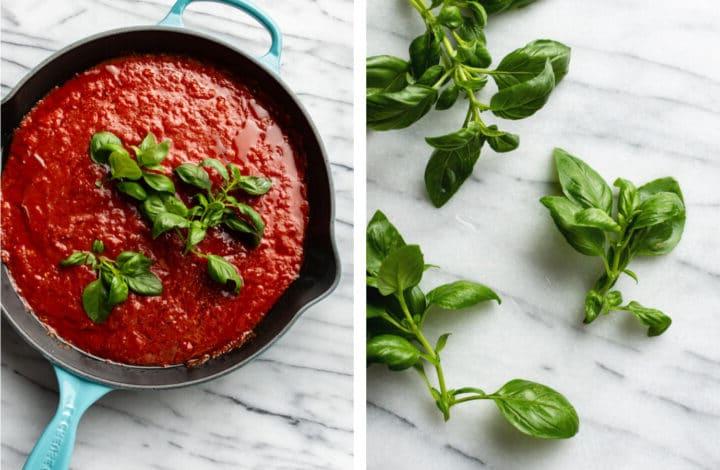 adding basil sprigs to a cast iron skillet with marinara sauce