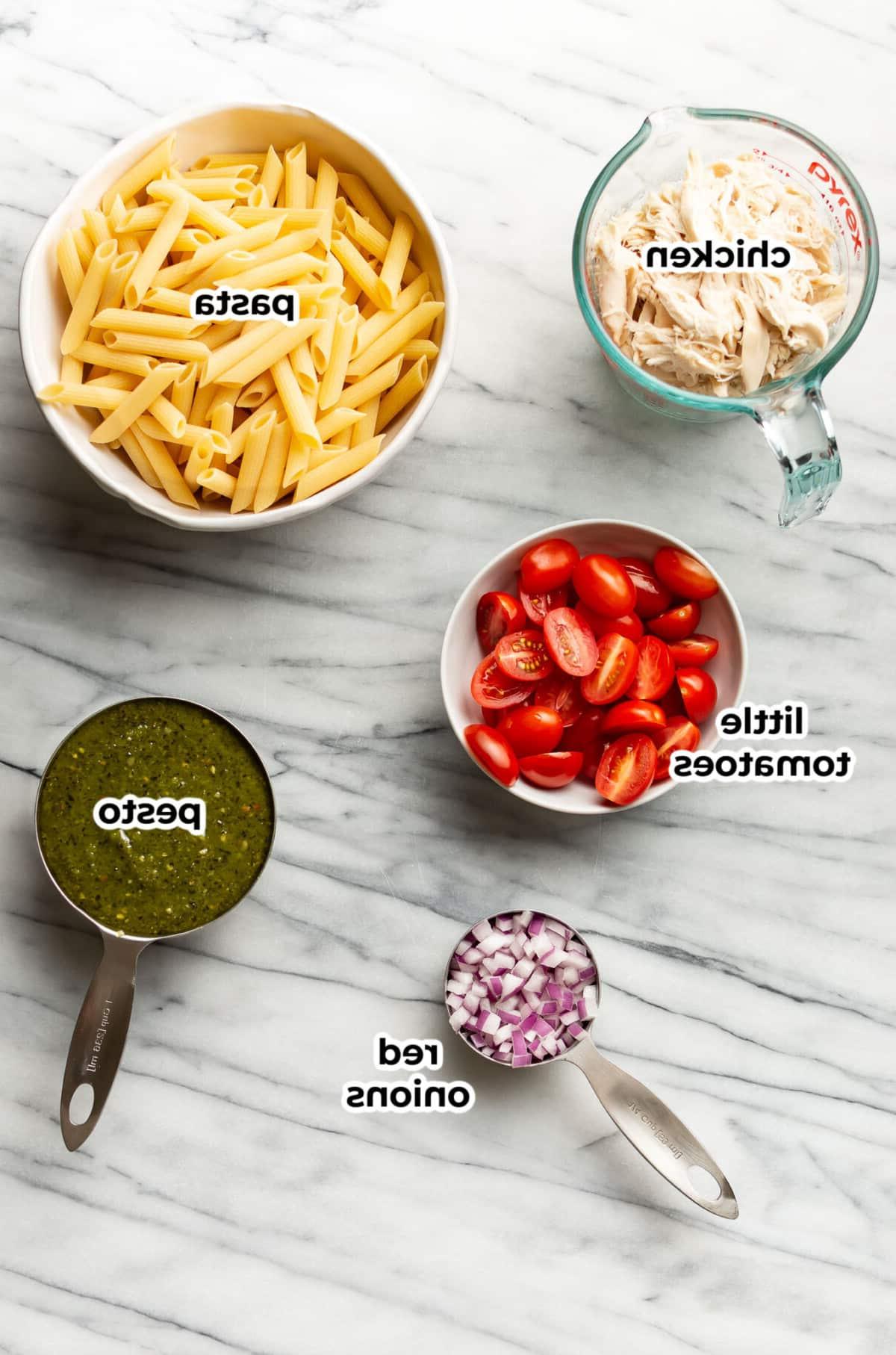 Zutaten für Hähnchen-Pesto-Nudelsalat übersichtlich in Zubereitungsschüsseln arrangiert.