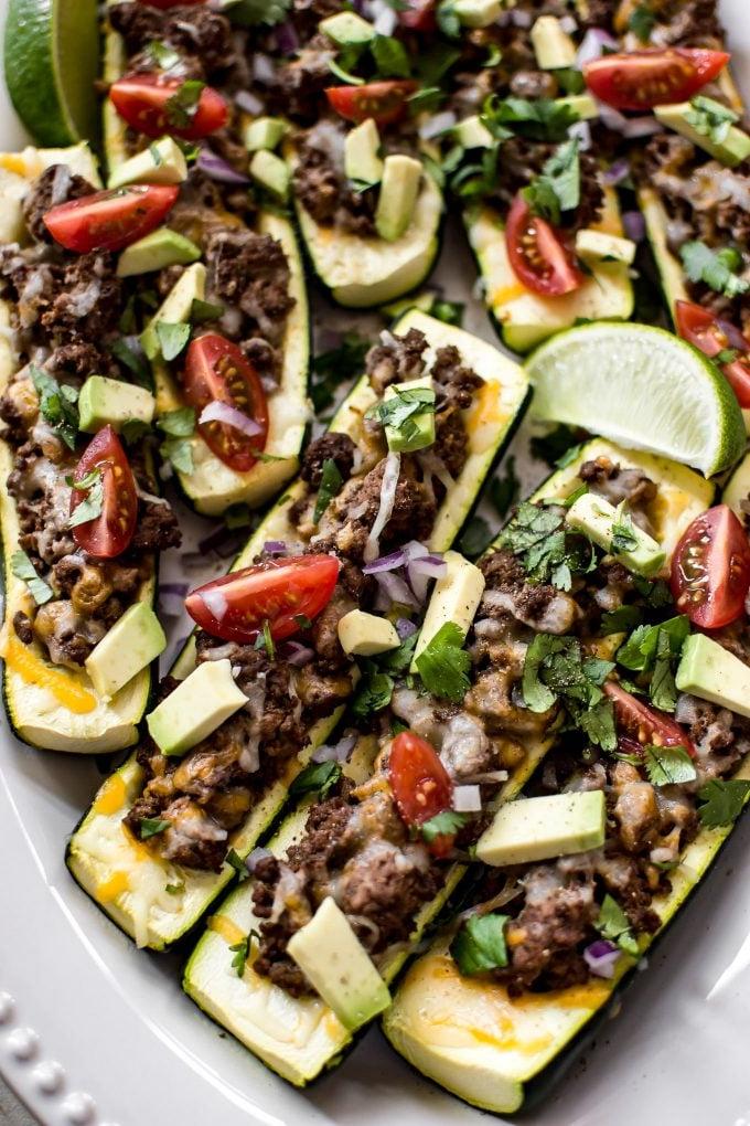 Nahaufnahme von mehreren kohlenhydratarmen Zucchini-Taco-Booten mit einer Limettenspalte.