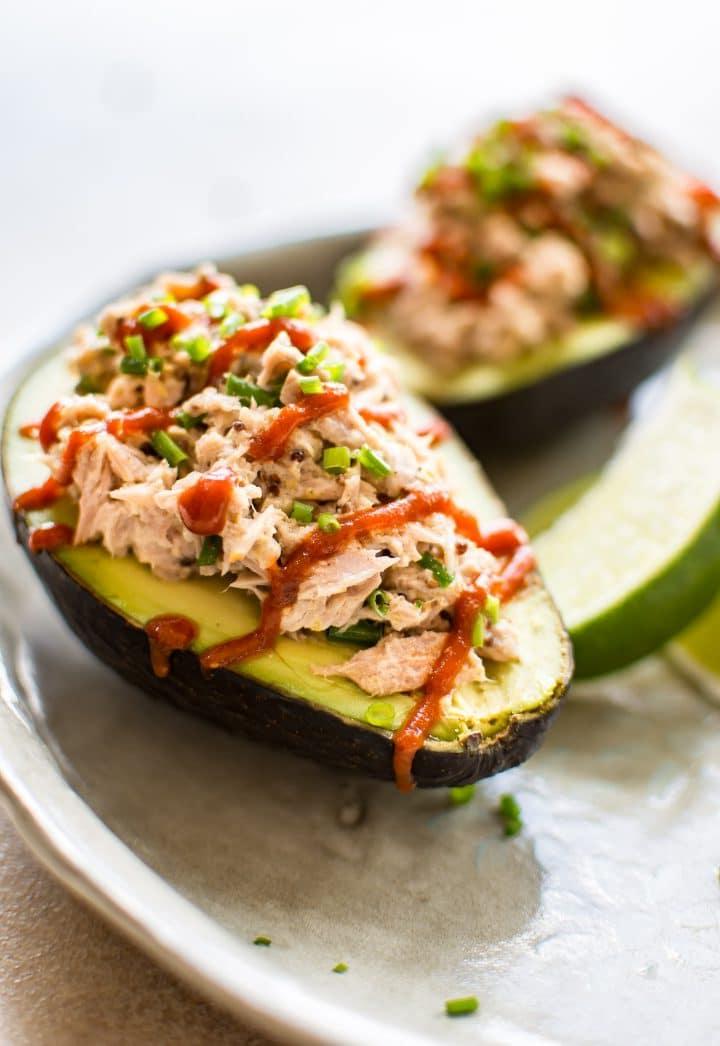 Teller mit zwei Hälften pikantem Sriracha-Thunfisch gefüllter Avocado und Limettenspalte
