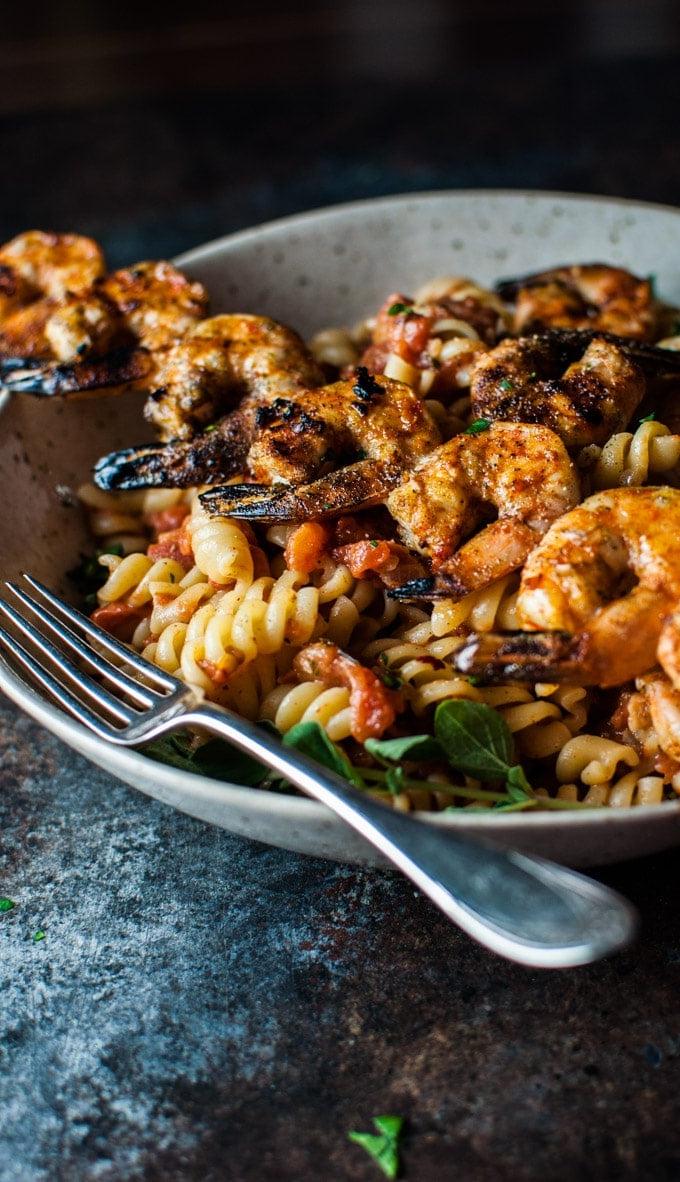 Nahaufnahme von würziger gegrillter Garnelen Pasta in einer Schüssel mit einer Gabel bereit zum Genuss.
