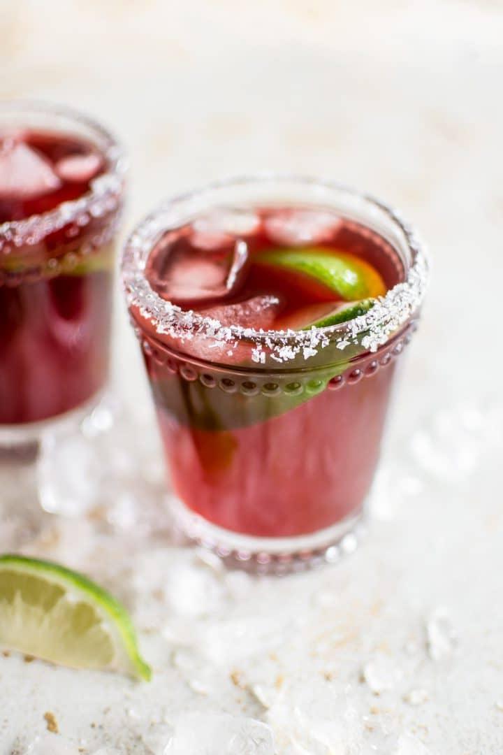 Zwei Granatapfel Margaritas in Gläsern mit Eis und Limettenspalten