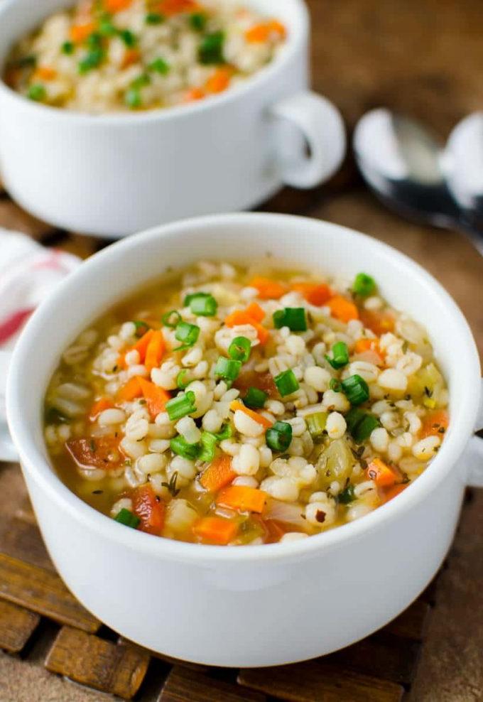 healthy barley soup with carrots in a white bowl