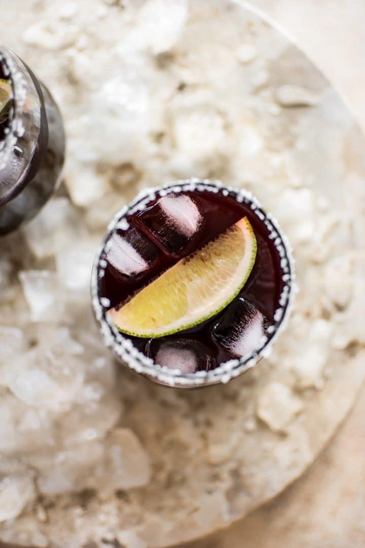 Schwarzkirsch-Margarita in einem Glas mit gesalzenem Rand und einem Limettenspalten