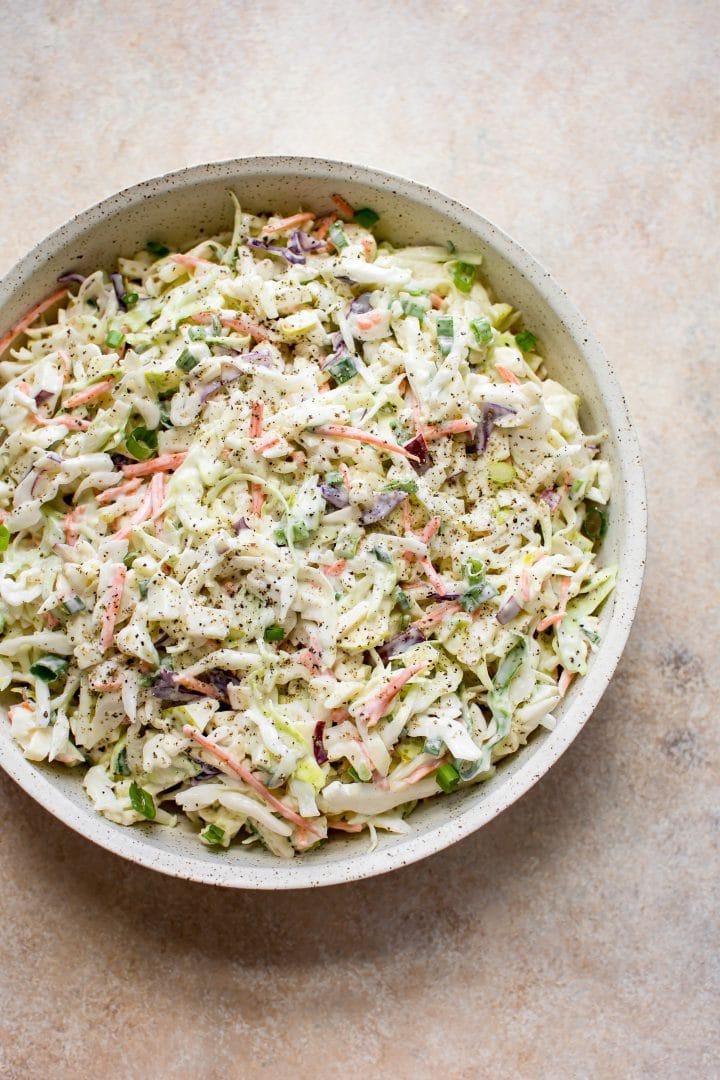 Apfel- und Kohl-Krautsalat mit cremigem Dressing in einer beigen Schüssel