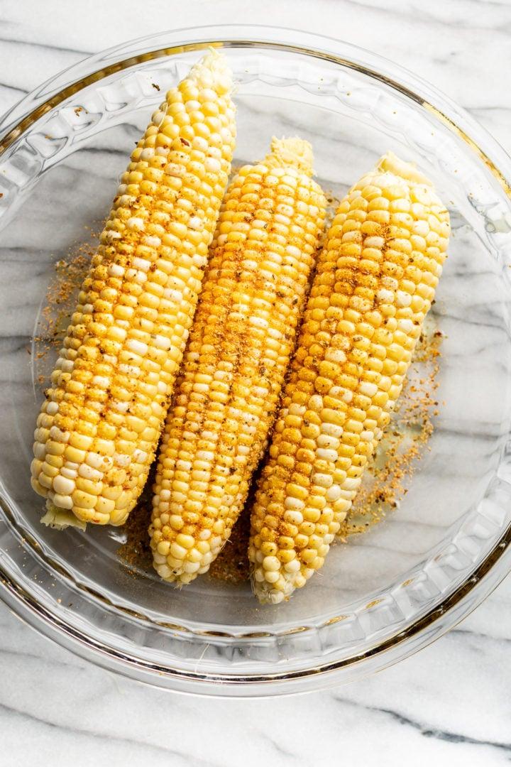 Maiskolben, bestrichen mit Olivenöl und Cajun-Gewürz, in einer Glaszubereitungsschale
