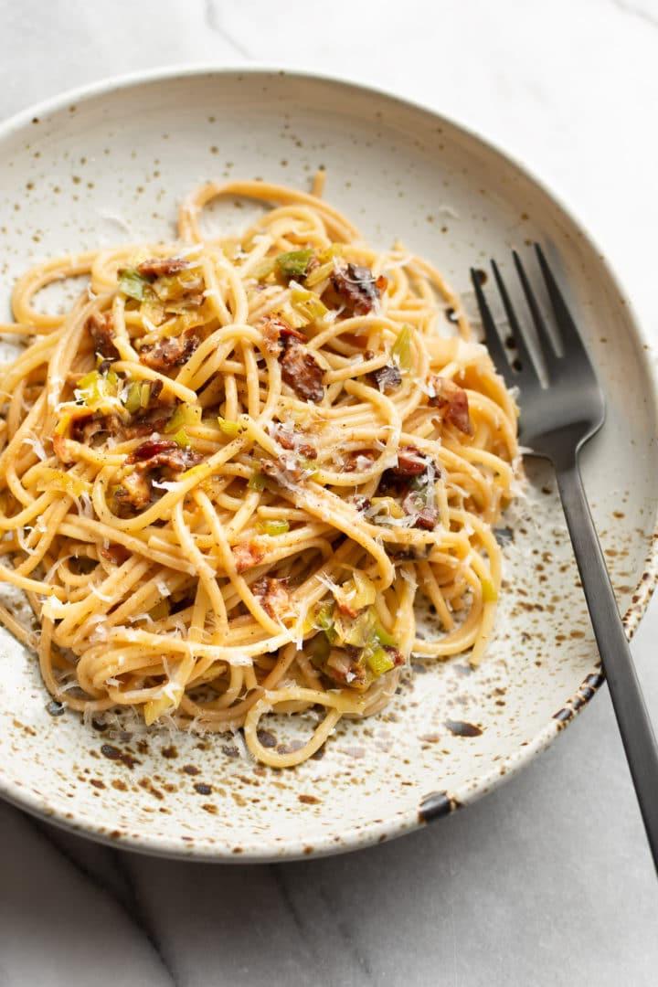 Speck-Lauch-Pasta in einer flachen Schale mit einer Gabel daneben