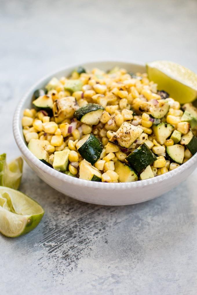 Schüssel mit einfachem gegrilltem Mais-Zucchini-Salat mit Limettenspalten