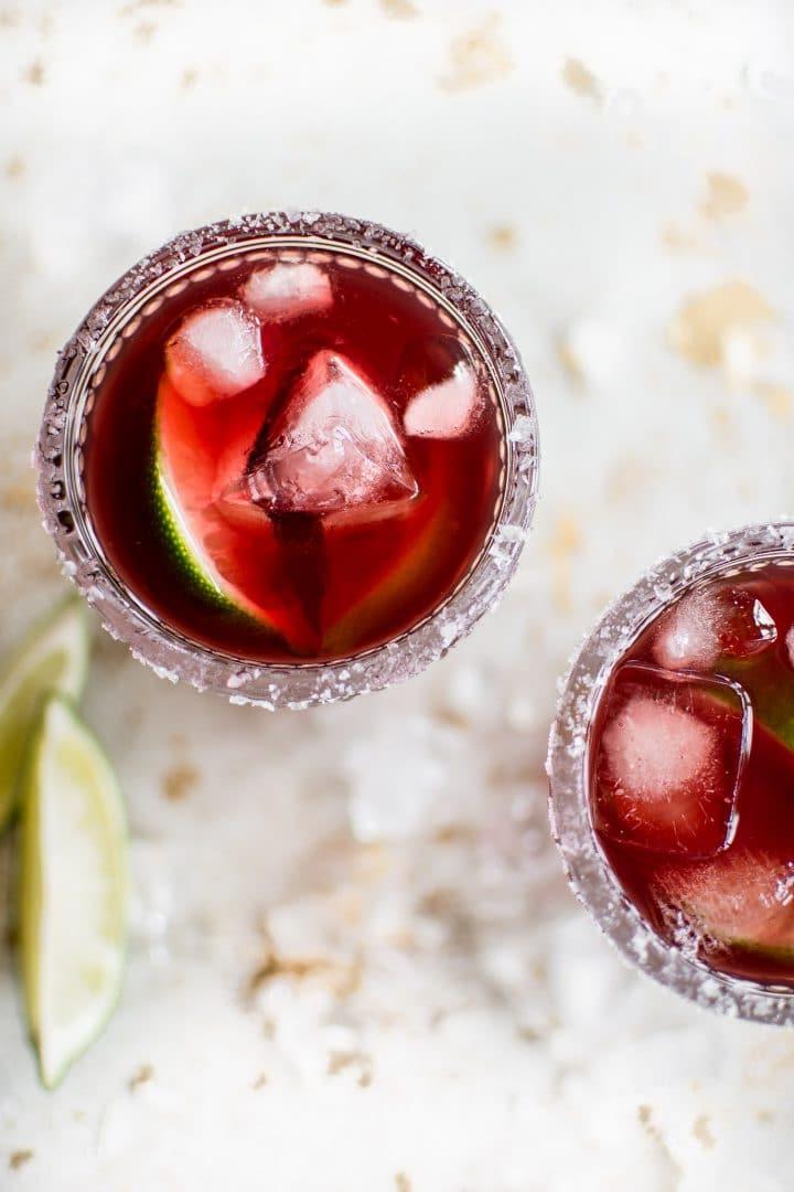 Granatapfel Margarita mit Eis in einem Glas und Limetten daneben