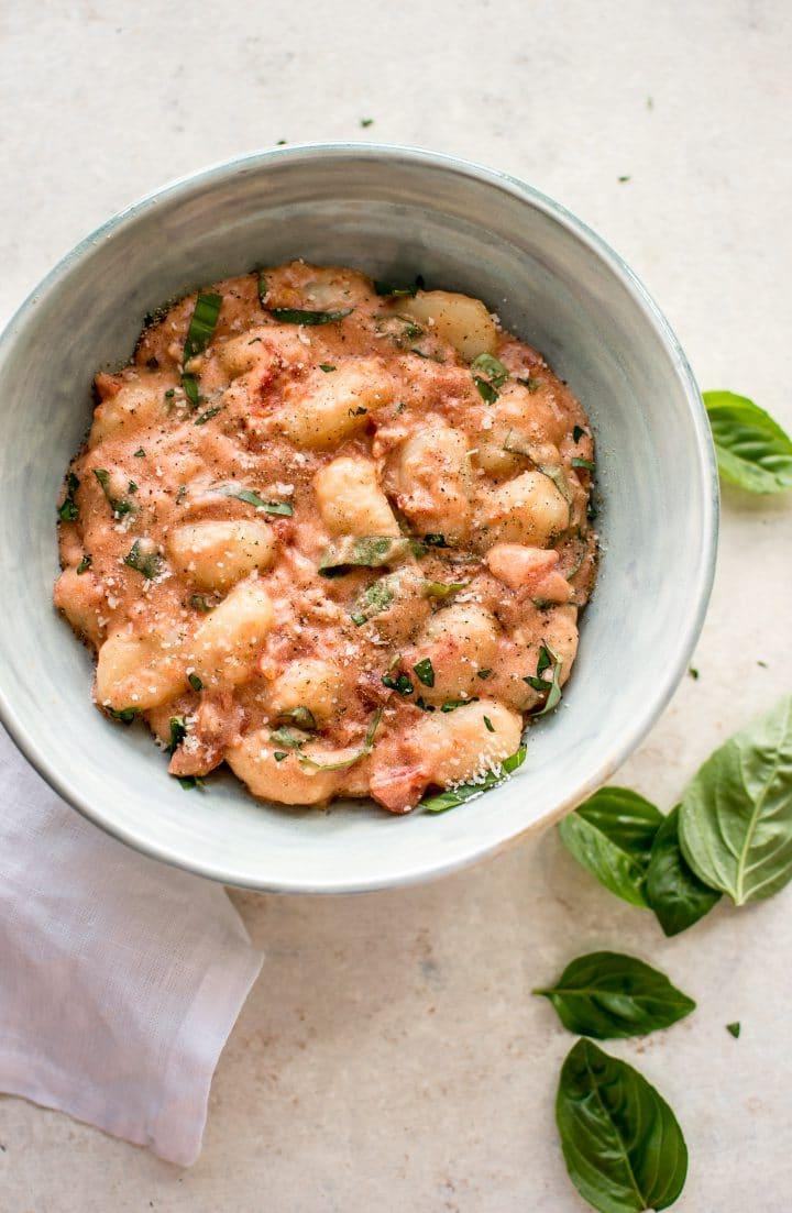 Schale mit Gnocchi alla Vodka neben Basilikumblättern