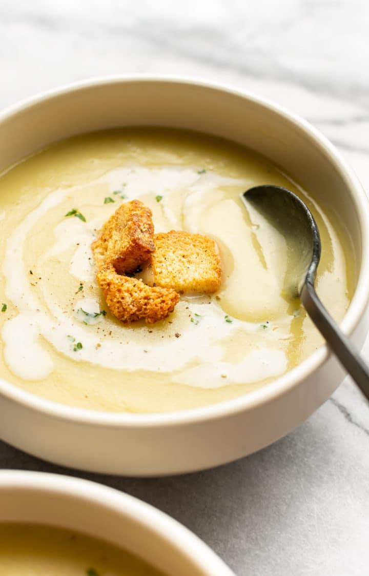 Einfache Kartoffel-Lauch-Suppe 5 Schüssel mit Kartoffel-Lauch-Suppe und einem Löffel