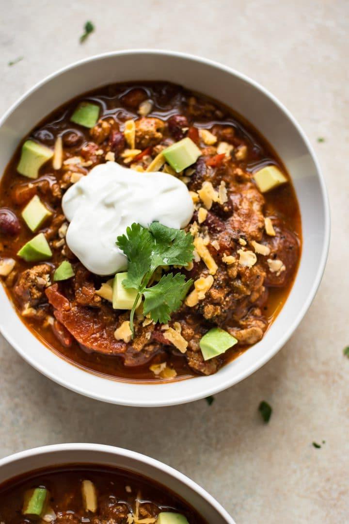 Weiße Schale mit Instant Pot Puten-Chili mit Bohnen, garniert mit Sauerrahm