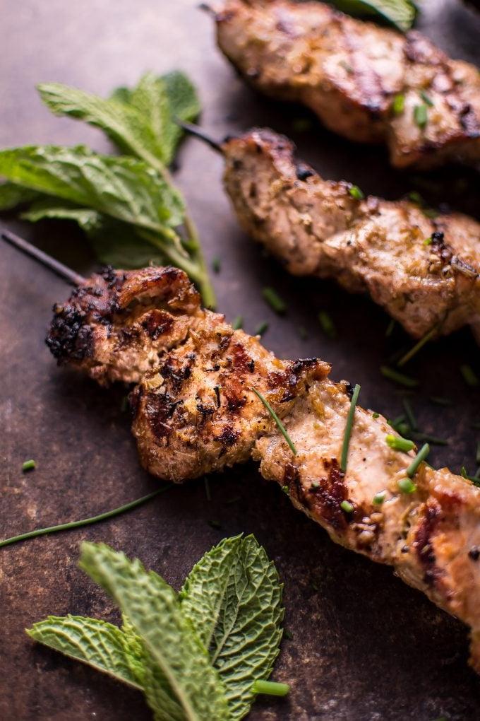 Nahaufnahme eines gegrillten vietnamesischen Zitronengras-Schweinefilet-Spießes mit Grillspuren und Minzzweig