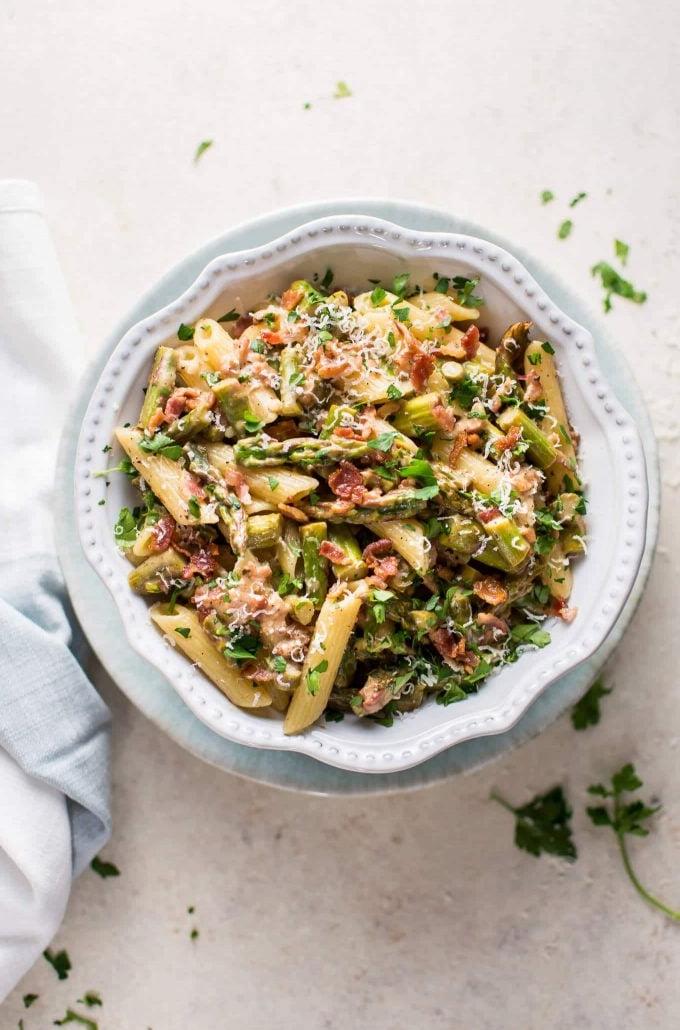 Schüssel mit frühlingshafter Spargel-Bacon-Pasta neben Stoffserviette