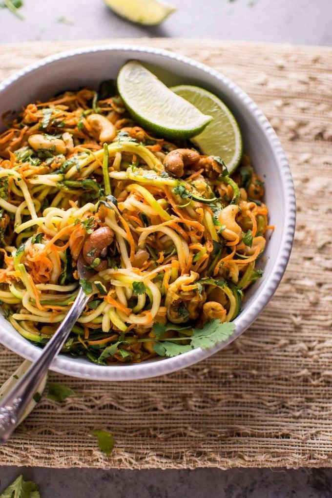 Ein Detailbild einer Schüssel veganer Knoblauch-Limetten-Cashew-Zoodles, mit einer Gabel bereit zum Genuss.