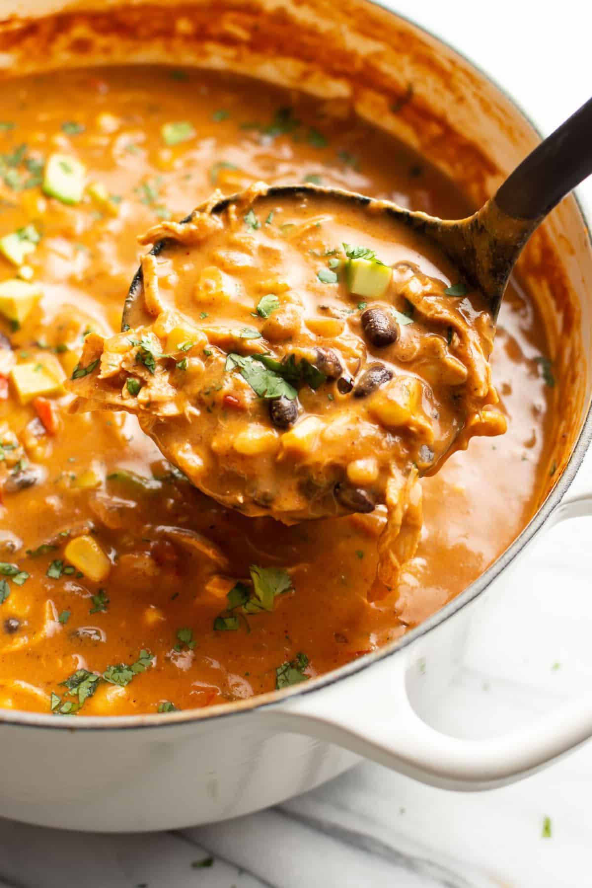 Ein Gusseisen-Bräter mit Hähnchen-Enchilada-Suppe und einer Schöpfkelle