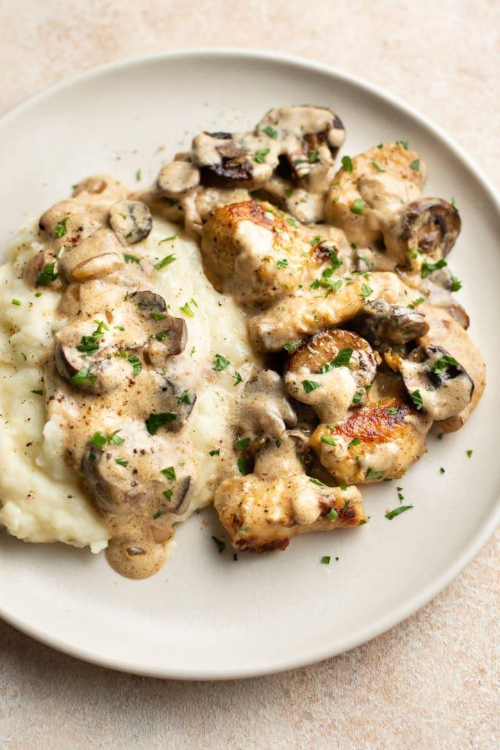 Hähnchen Stroganoff auf einem beigen Teller mit Kartoffelpüree und viel Soße