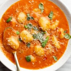 Cremige Tomaten-Gnocchi-Suppe 6 Eine Schüssel cremige Tomaten-Gnocchi-Suppe mit einem Löffel