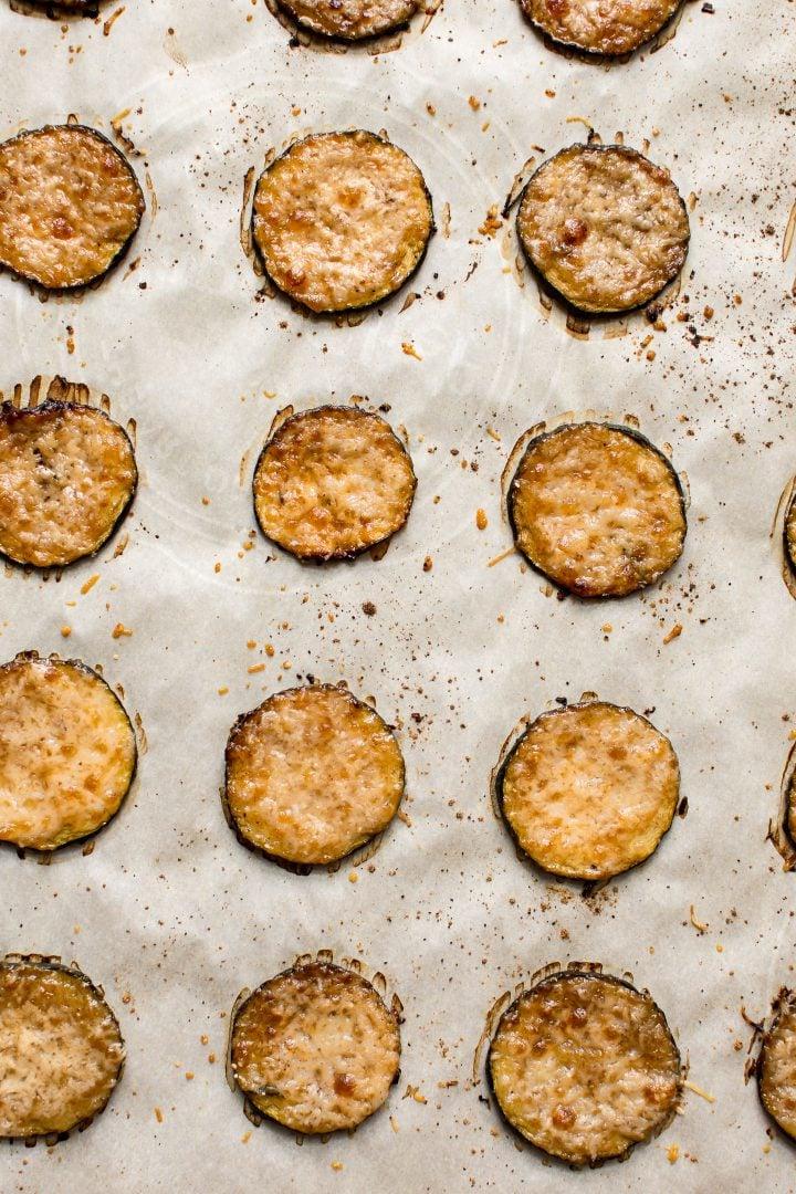 Nahaufnahme von Low-Carb Zucchini-Scheiben mit Parmesan auf einem Backblech