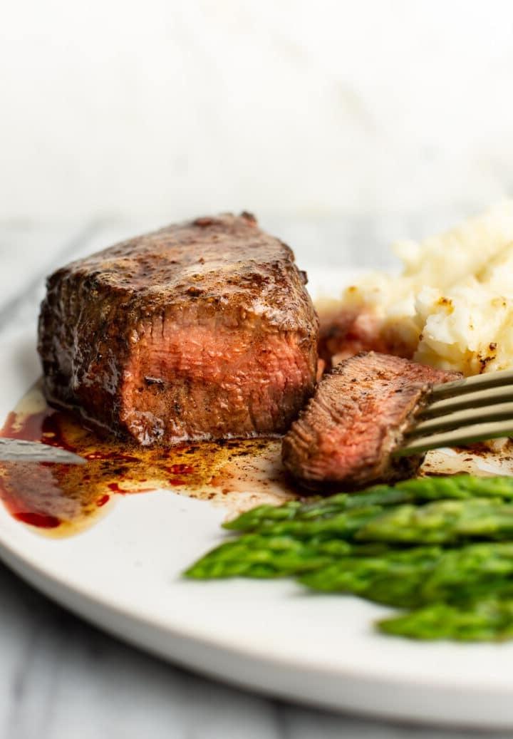 Filet Mignon auf einem Teller mit Gabel, Kartoffelpüree und Spargel
