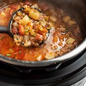 Ein Instant Pot mit einer Schöpfkelle Rinderhackfleischsuppe