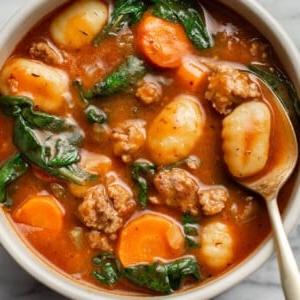 Ein Teller Wurst-Gnocchi-Suppe mit einem Löffel
