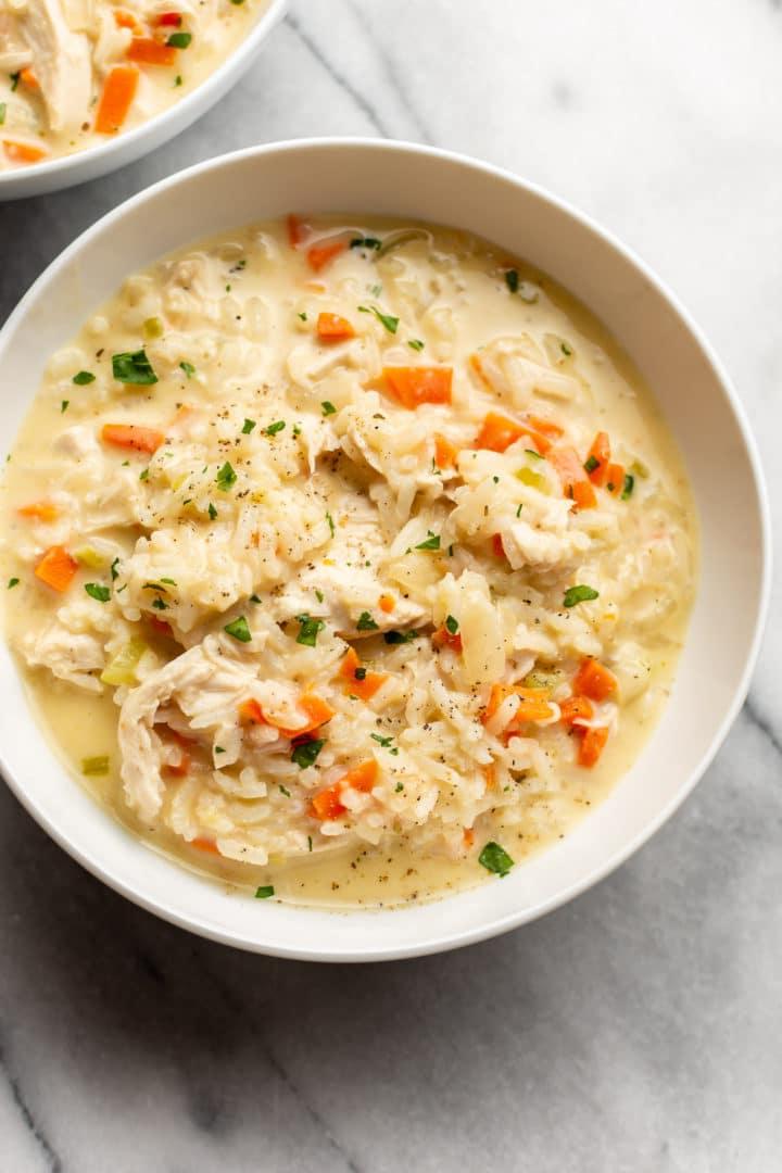 Cremige Hühner-Reis-Suppe 7 Nahaufnahme einer cremigen Hähnchen-Reis-Suppe in einer weißen Schüssel.