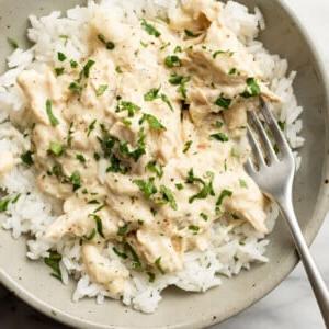Eine Schale mit italienischem Hähnchen aus dem Slow Cooker über Reis mit einer Gabel