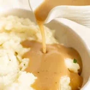 pouring brown gravy onto mashed potatoes