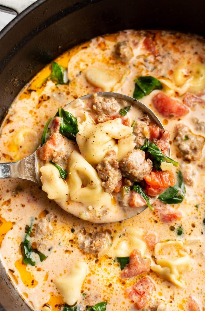 Italienische Salsiccia-Tortellini-Suppe 7 Nahaufnahme einer Schöpfkelle in einem Suppentopf mit cremiger italienischer Wurst-Tortellini-Suppe