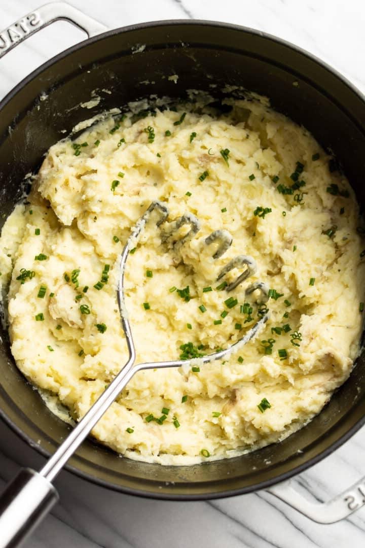Ein Topf Boursin Kartoffelpüree mit einem Stampfer
