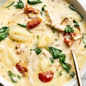 Ein Teller mit cremiger Toskanischer Hähnchen-Gnocchi-Suppe und einem Löffel