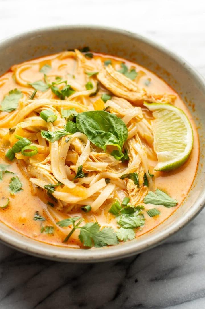 Eine Schüssel mit Thai Hähnchen-Curry-Suppe, garniert mit einer Limettenspalte